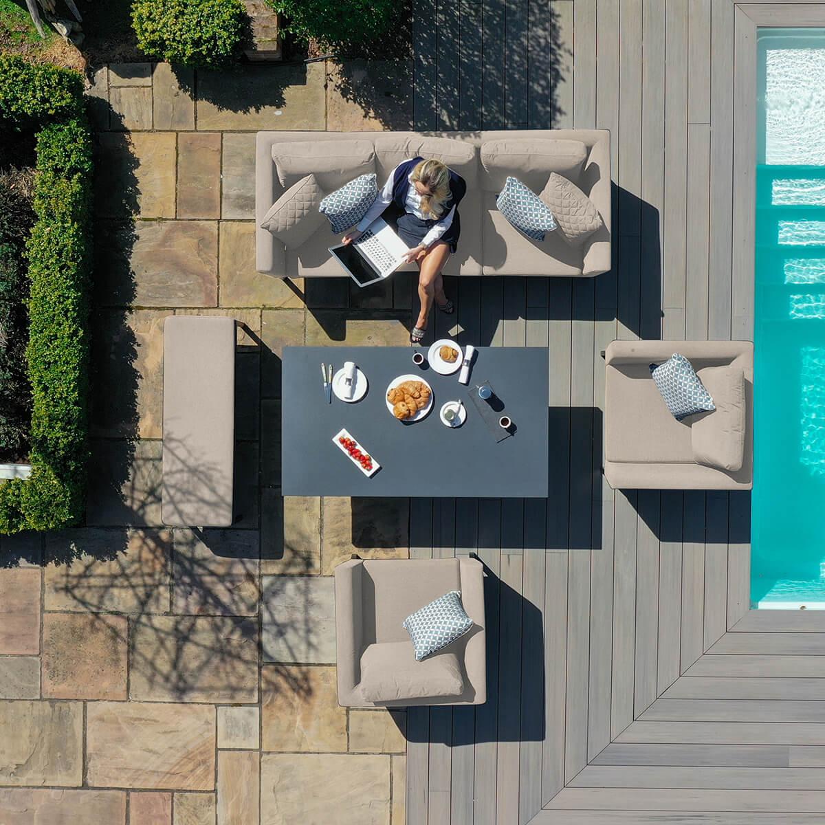 Outdoor garden sofa set with cushions and dining table by pool on patio