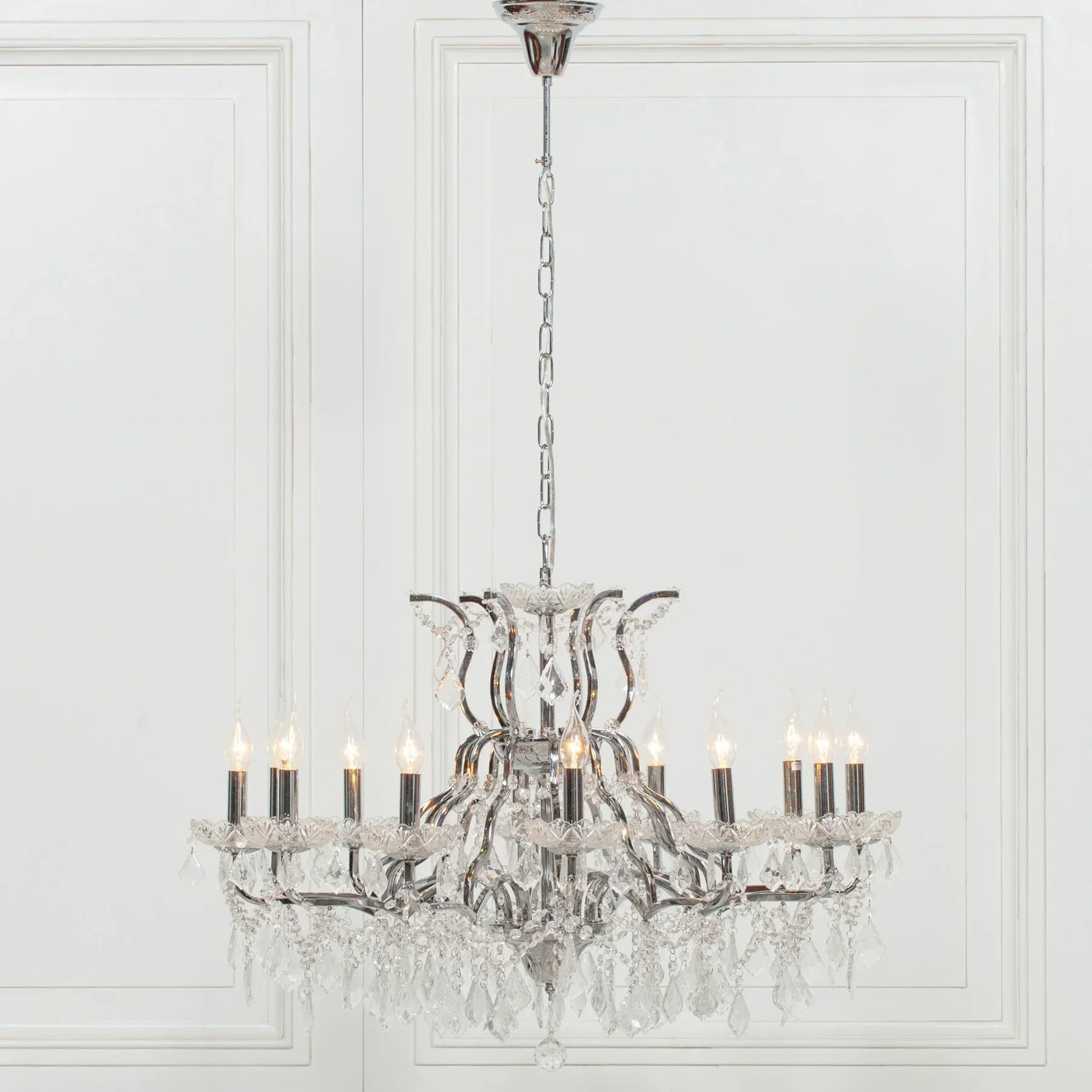Crystal chandelier with chrome frame and twelve candle-style lights hanging from ceiling
