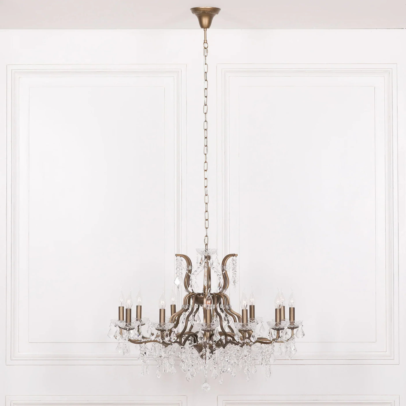 Antique brass chandelier with crystal accents hanging in elegant white room