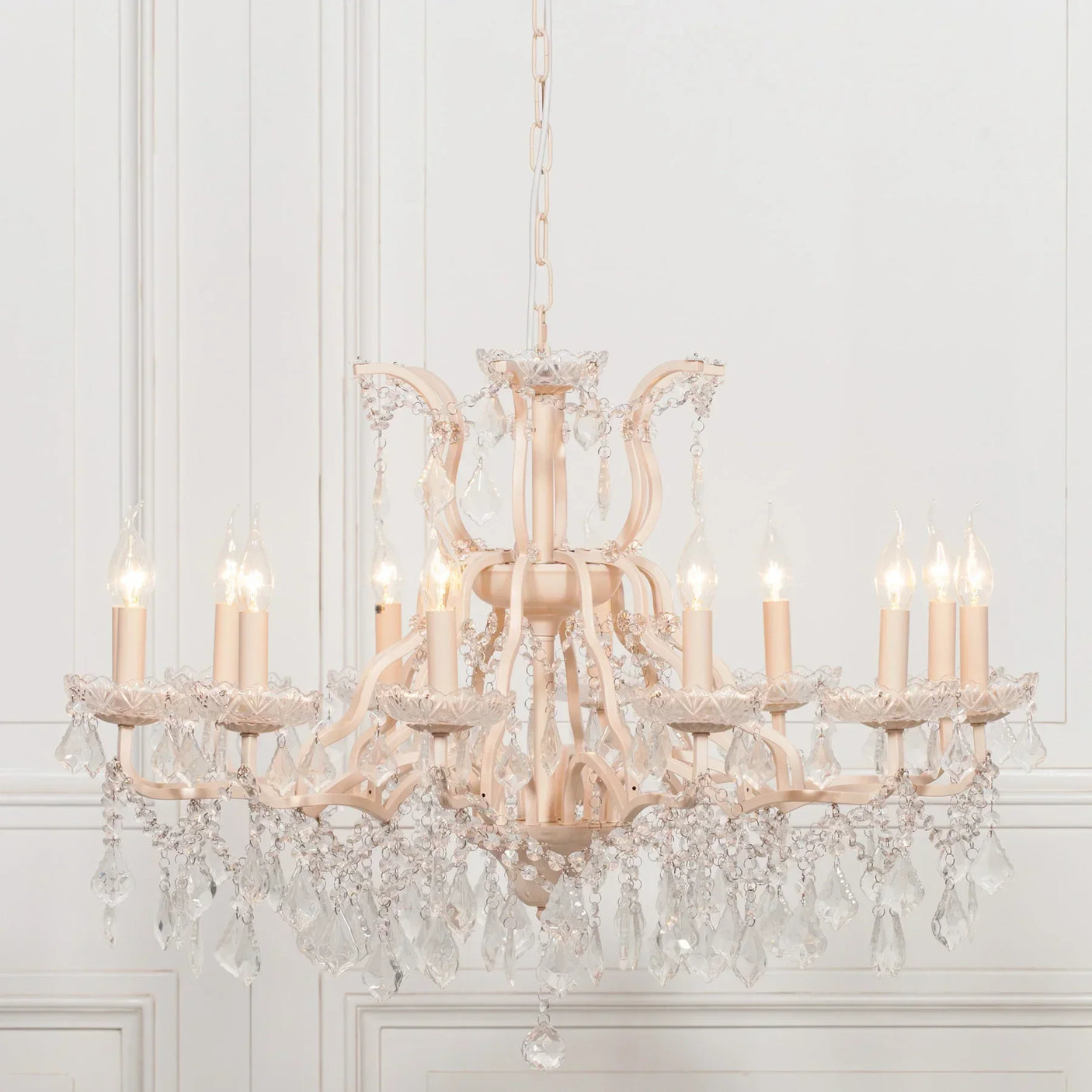 Ivory crystal chandelier with candle bulbs and hanging glass droplets in elegant room