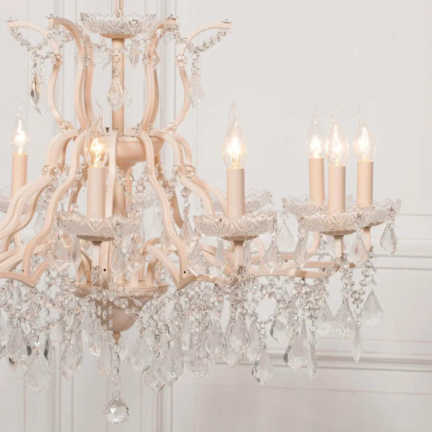 Cream crystal chandelier with hanging glass droplets and candle style bulbs in a white room