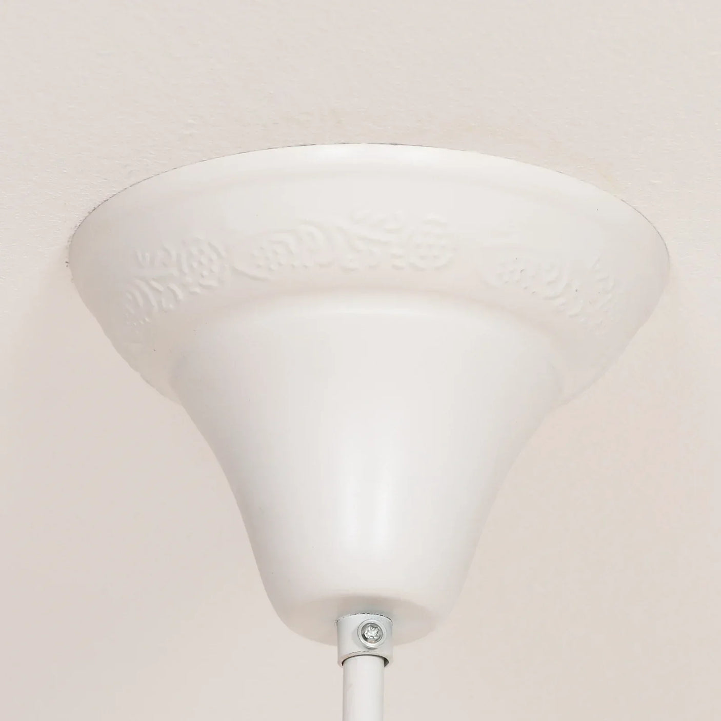 White ceiling light rose with subtle floral detail and metal fitting close-up