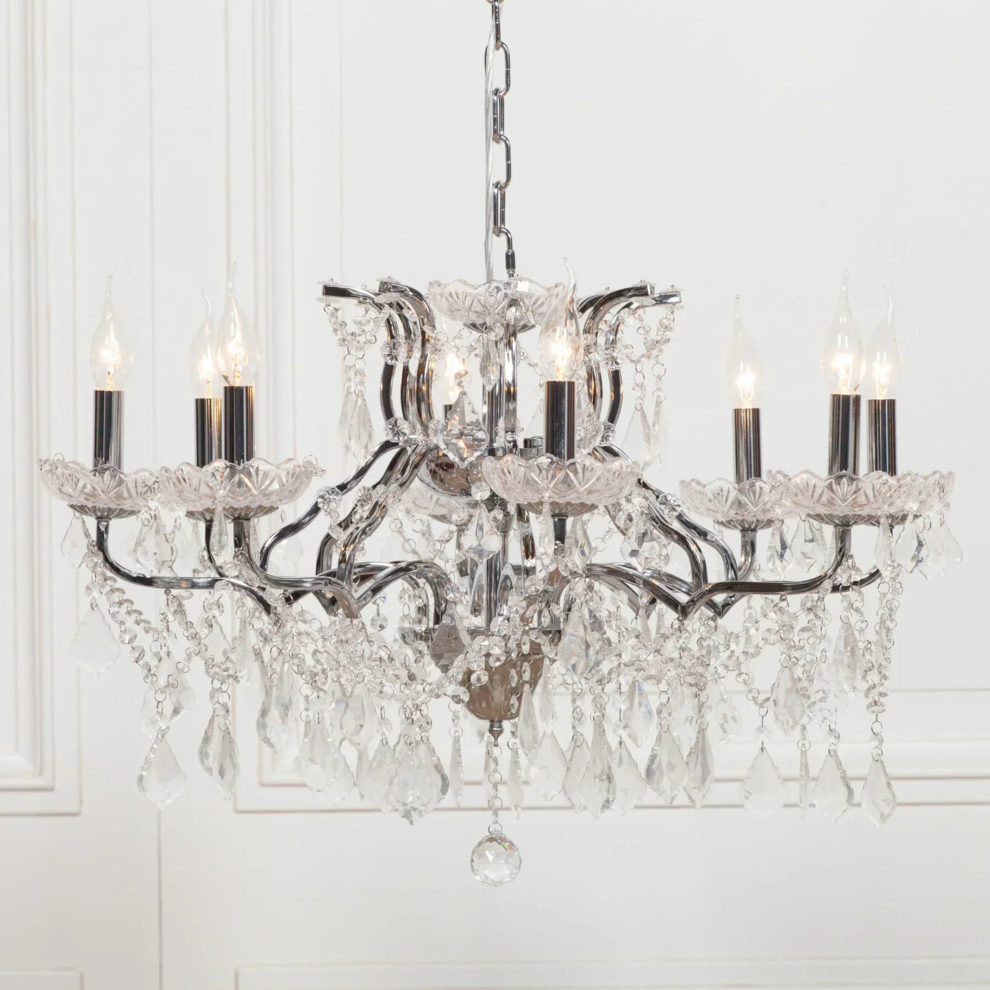 Crystal chandelier with chrome frame and candle-style lights hanging in a bright room