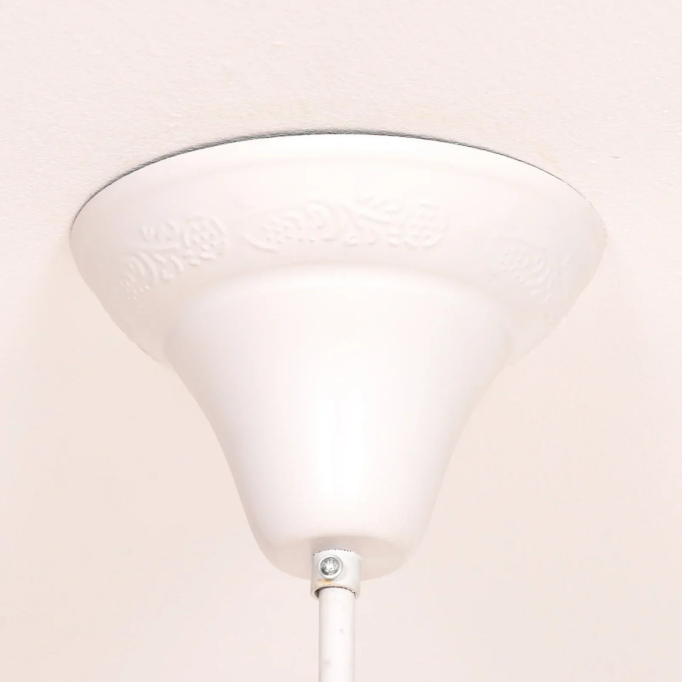 White ceiling rose with subtle floral pattern and metal light fitting