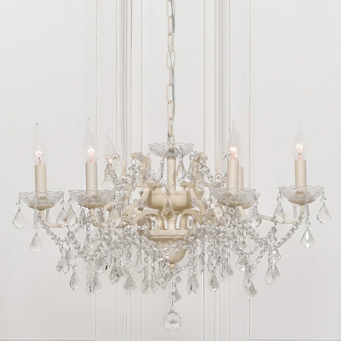 Crystal chandelier with six candle-style lights and hanging glass pendants in cream finish