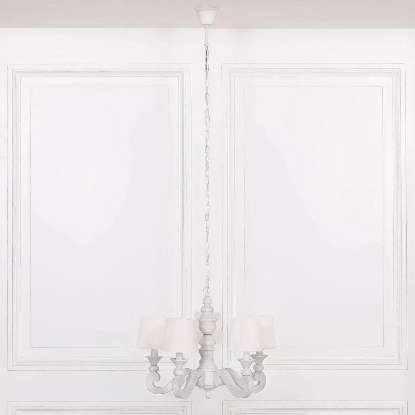 White wood chandelier with five fabric lampshades suspended in a classic room setting