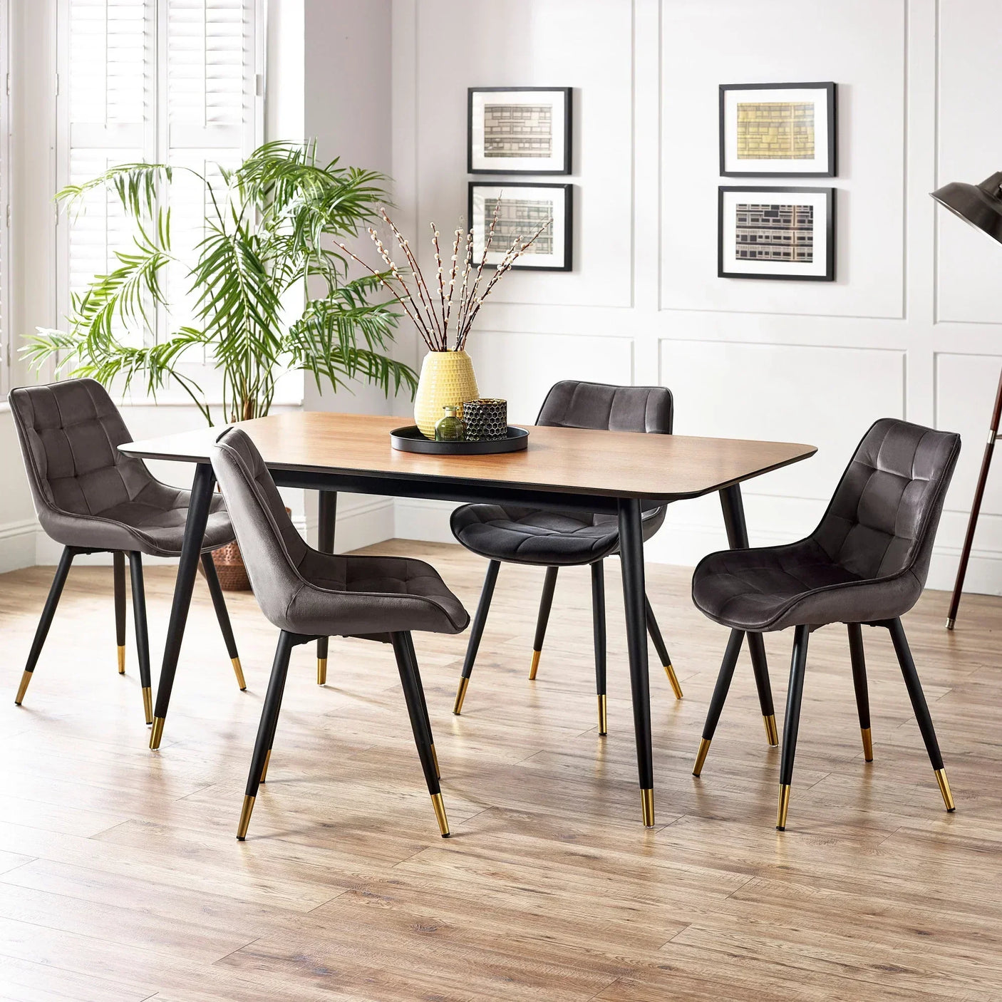 Contemporary dining table set with four grey velvet chairs and gold-tipped black legs