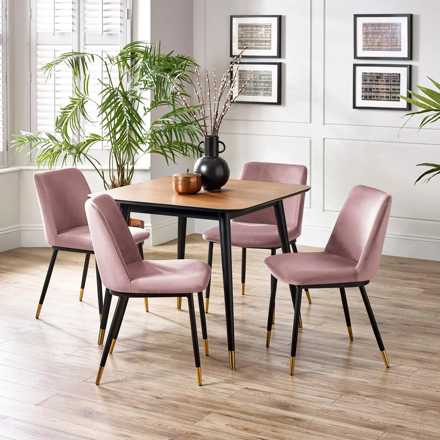 Modern dining table with wood top and four pink velvet chairs with gold tip legs