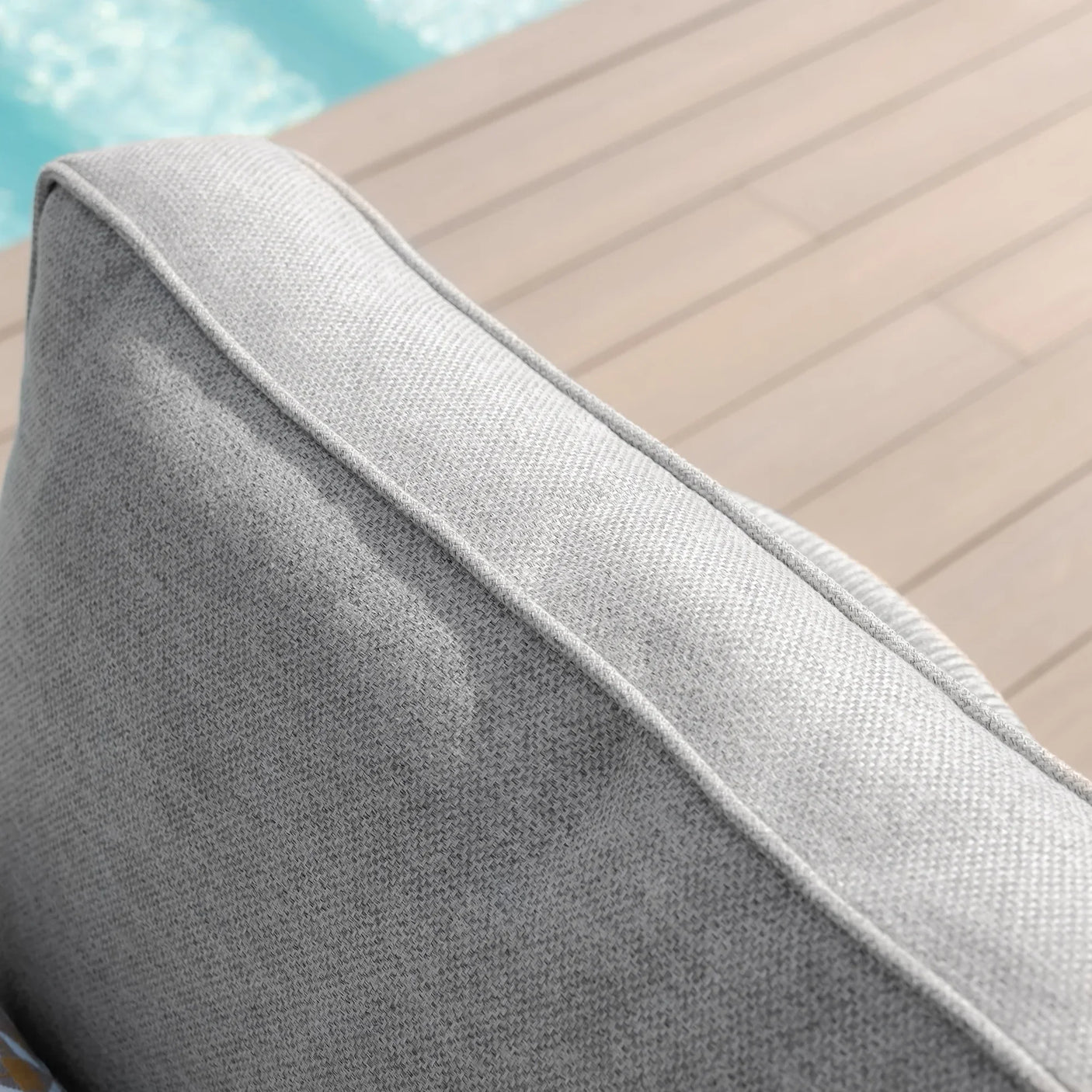 Close-up of grey outdoor sofa cushion with textured fabric by poolside decking