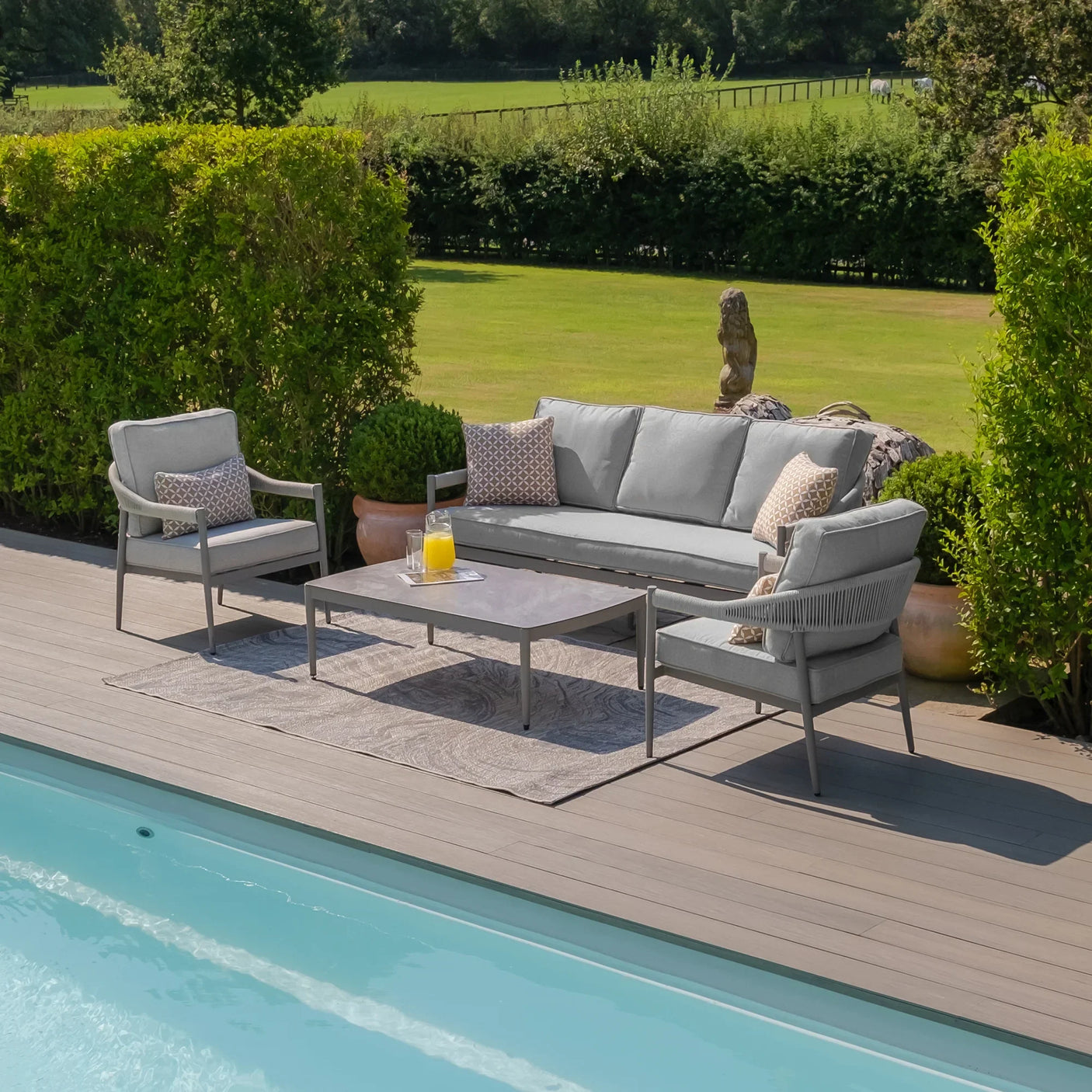 Grey outdoor sofa set with armchairs and coffee table beside a pool on garden decking