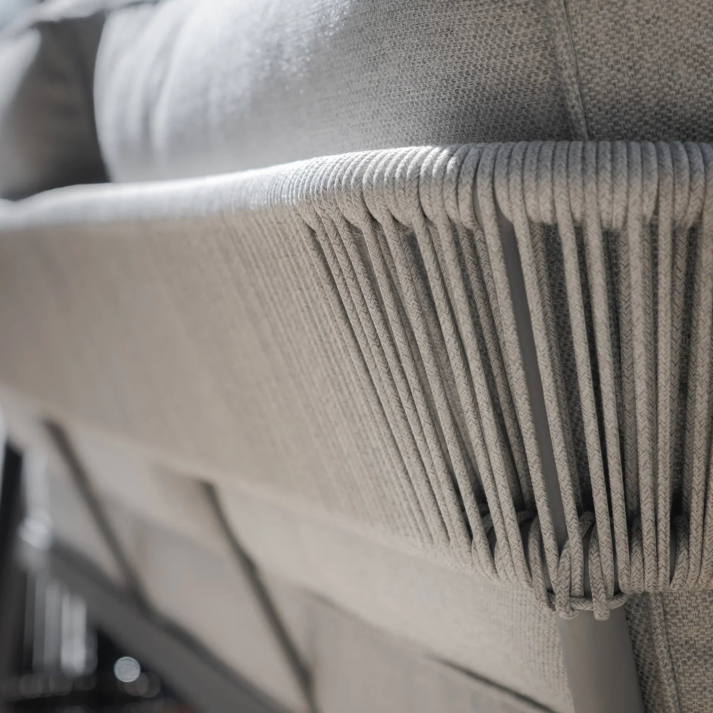 Closeup of grey outdoor sofa backrest with woven rope detail and textured fabric cushions