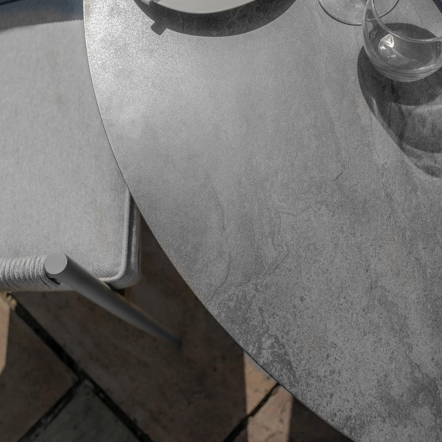 Close view of grey stone outdoor dining table with matching chair and tableware