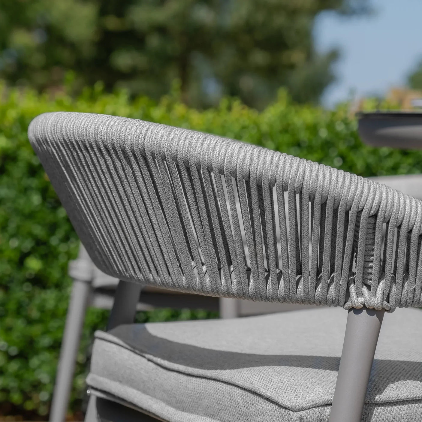Grey rope garden chair with padded seat and outdoor greenery background