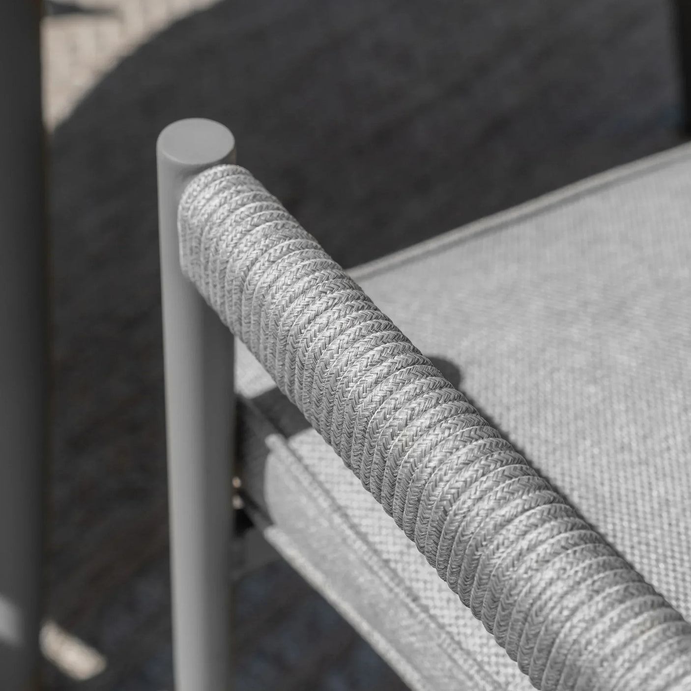 Closeup of grey rope armrest and seat cushion detail on outdoor dining chair