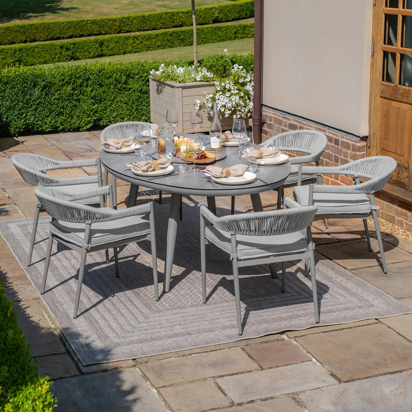 Grey outdoor dining set with six chairs and round table set for alfresco meal on patio