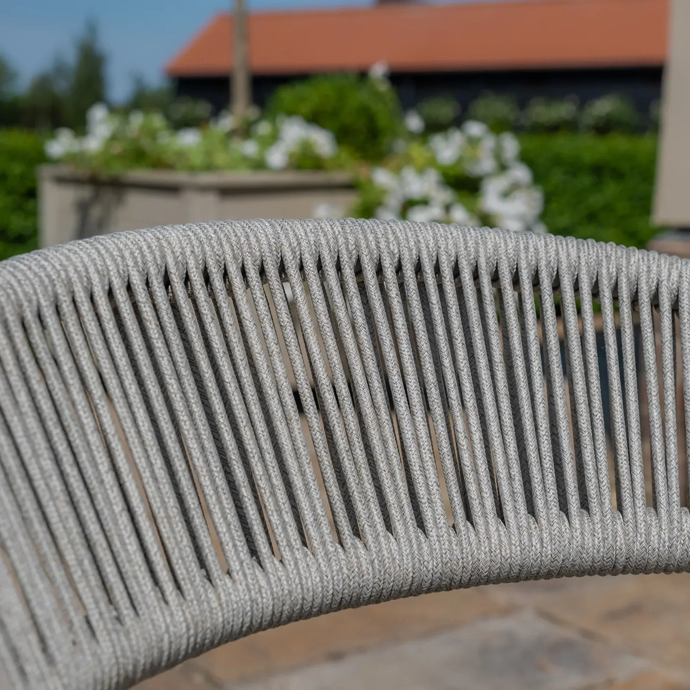 Close-up of grey rope outdoor chair backrest with garden background
