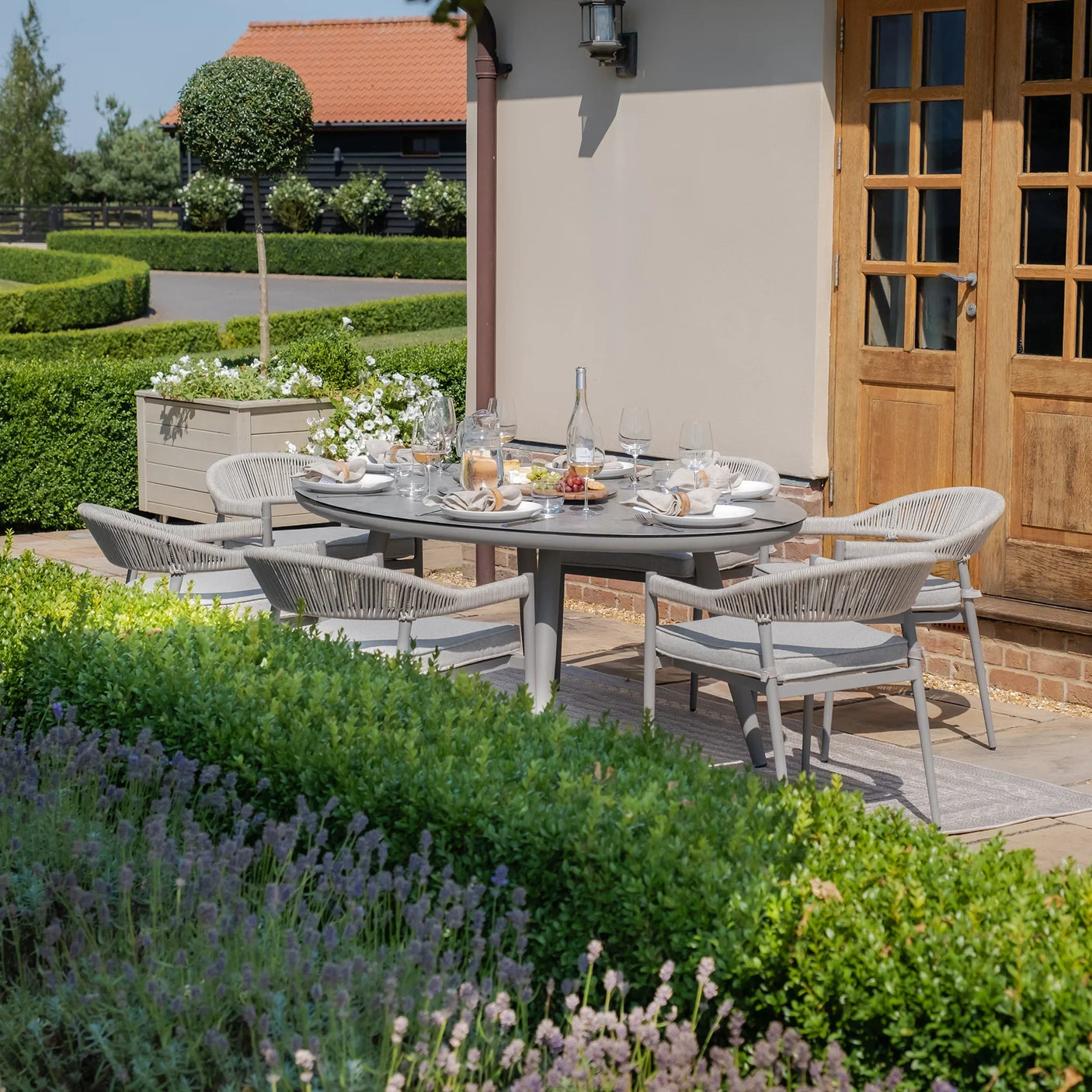 Grey outdoor dining table set with six chairs on patio, table set for alfresco dining