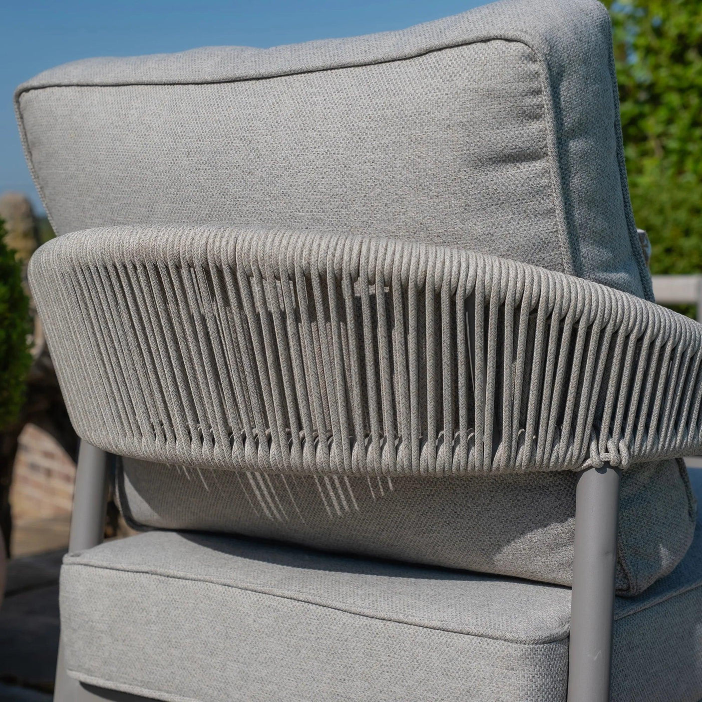 Close-up of grey outdoor lounge chair with rope weave back and padded cushions