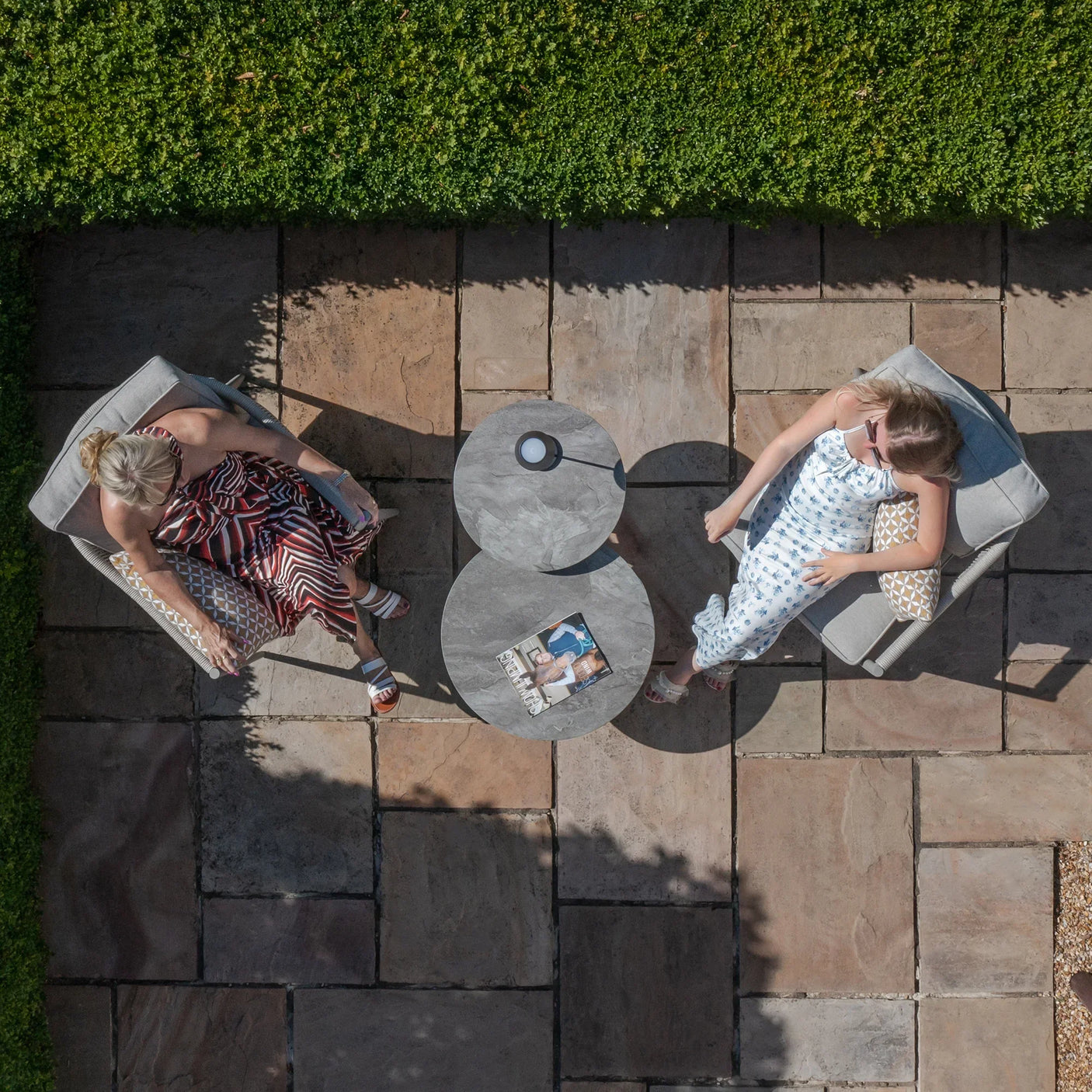 Garden lounge set with two grey cushioned armchairs and twin circular patio coffee tables