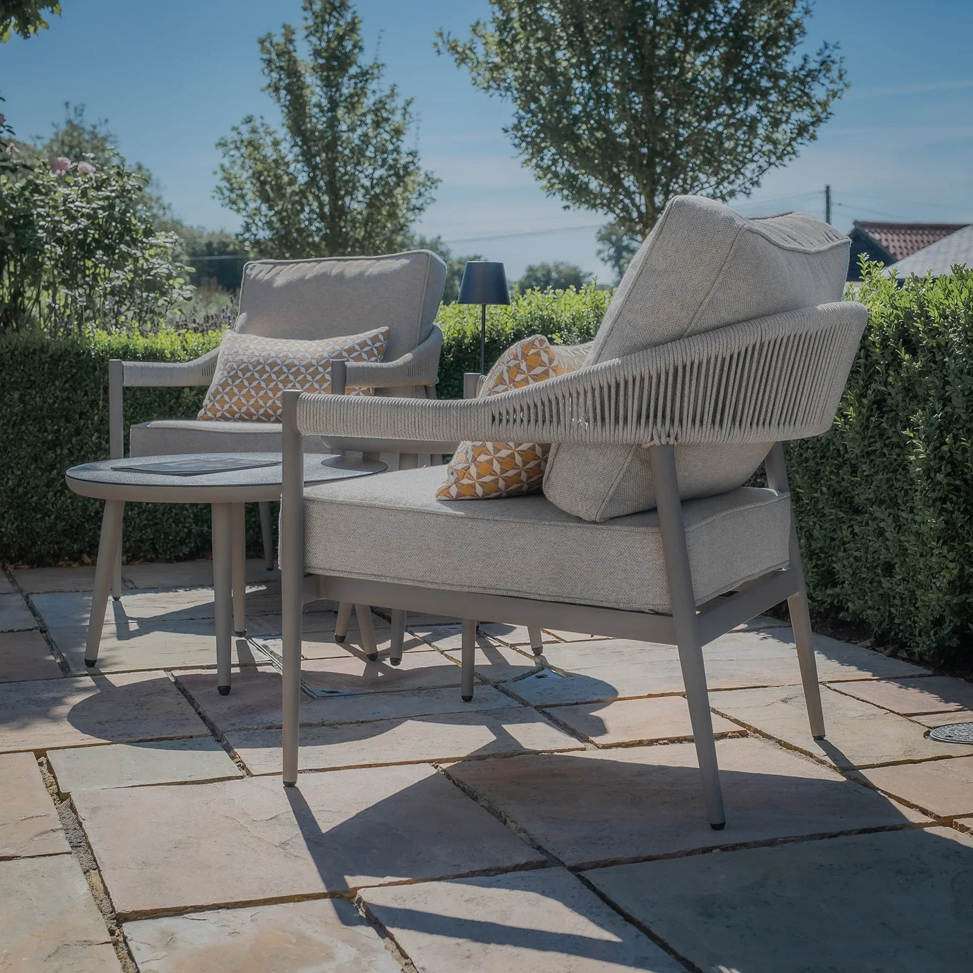 Grey outdoor garden lounge set with rope detail and cushions on stone patio