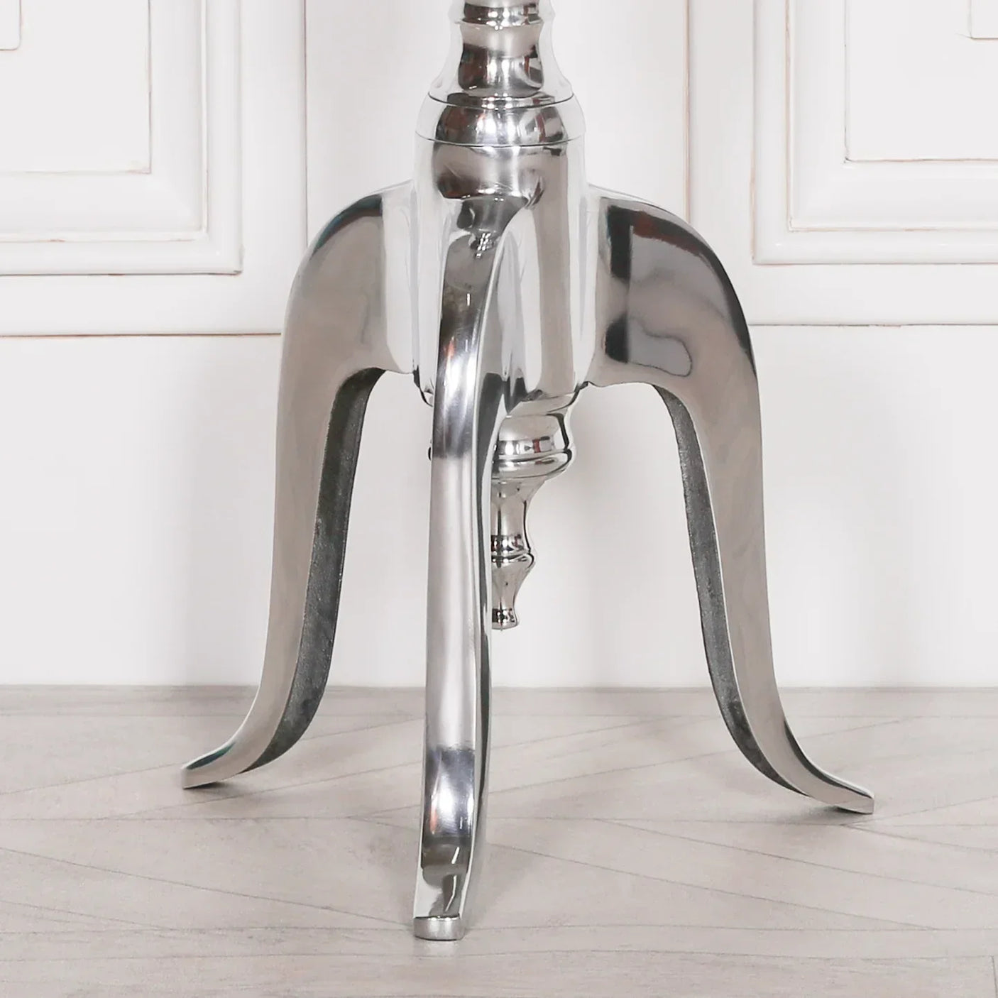 Close-up of polished metal furniture leg with curved design on light wood floor
