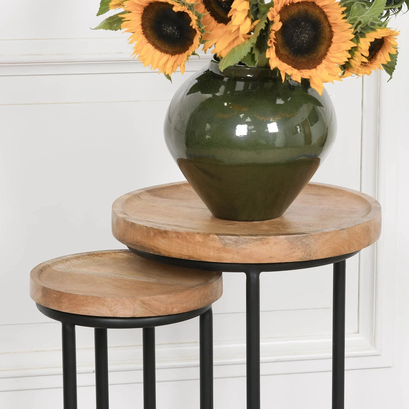 Round nesting side tables with wooden tops and black metal legs, vase of sunflowers on top
