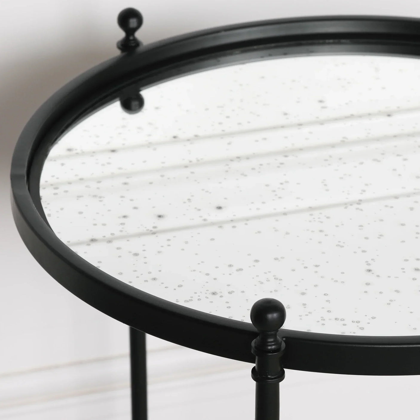 Round black metal side table with speckled glass top close-up
