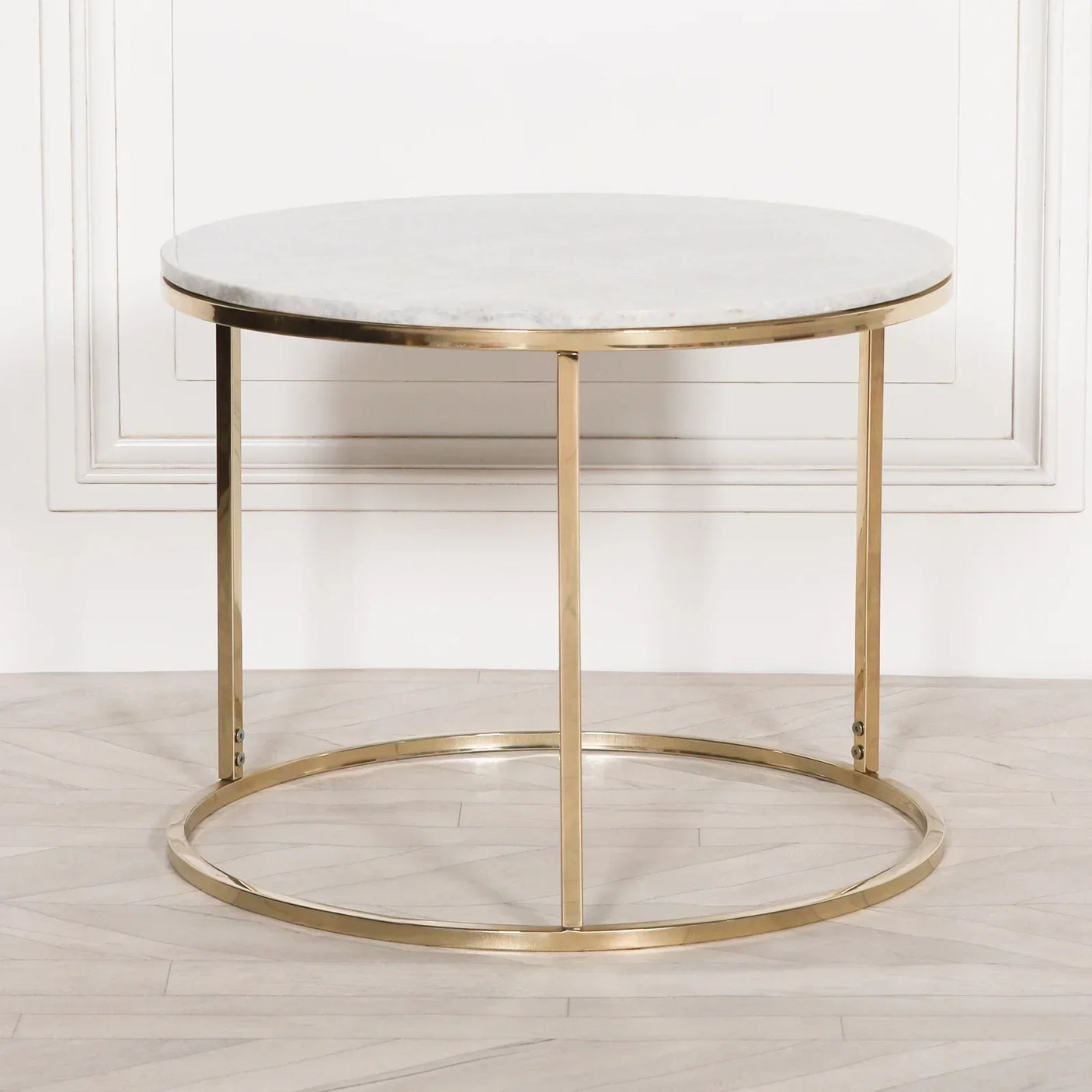 Round marble coffee table with gold metal frame on light wood floor