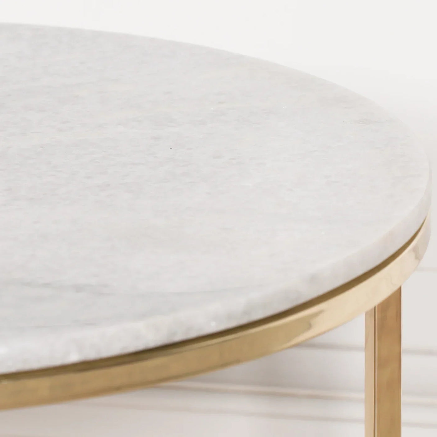 Round marble coffee table with gold metal frame, close-up of tabletop and edge detail
