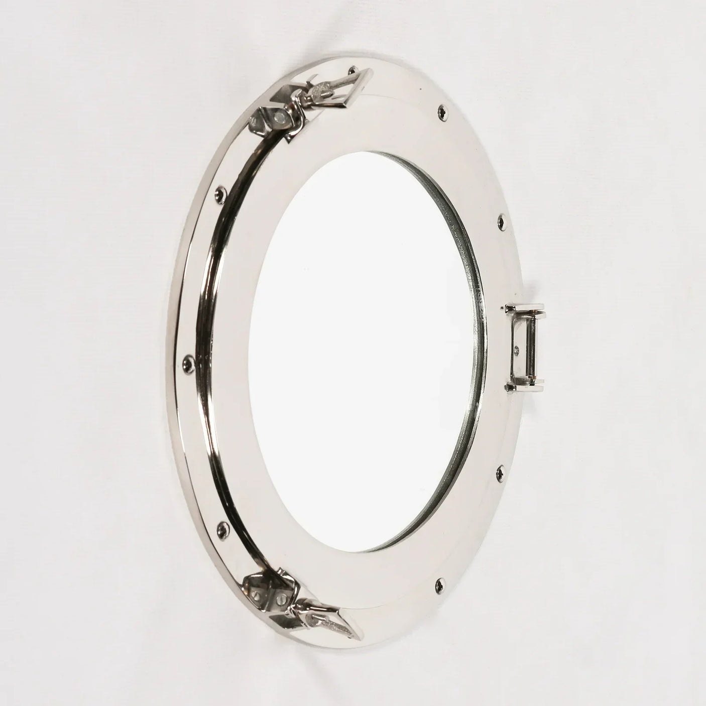 Chrome round porthole mirror with visible hinges and bolts on white wall, angled view