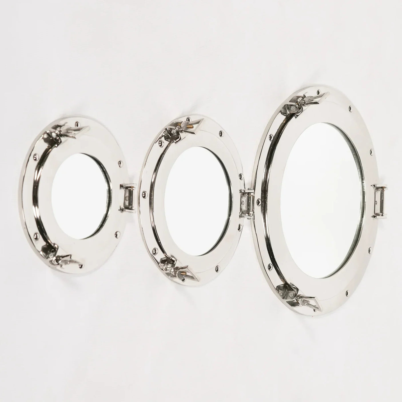 Set of three round porthole mirrors with chrome frames on a white wall