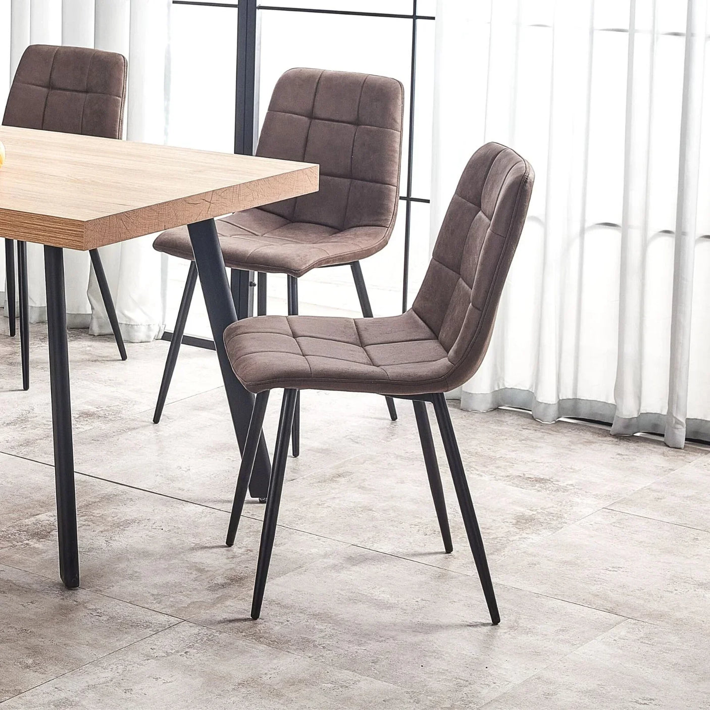 Brown velvet dining chairs with black metal legs around light wood dining table