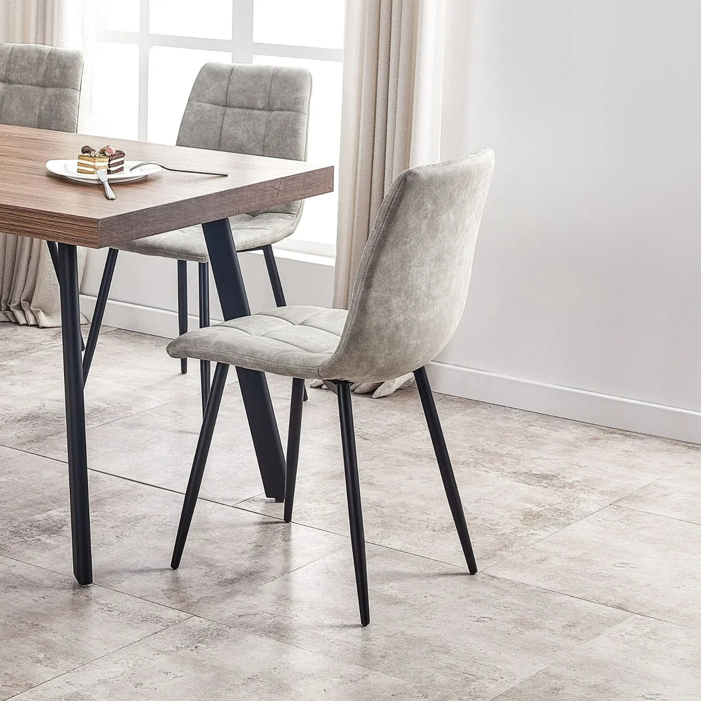 Light grey upholstered dining chairs with black legs around wooden dining table