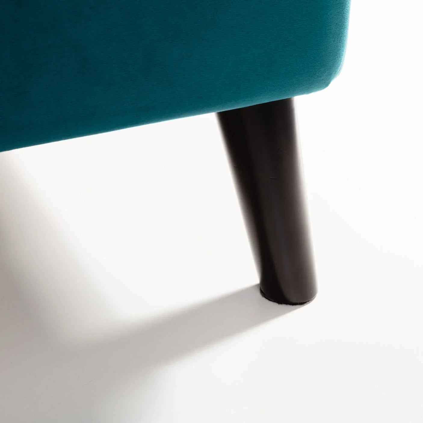 Teal velvet king bed corner showing black tapered leg detail on white background