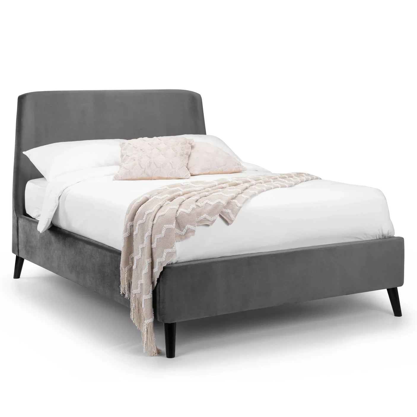Grey velvet king bed with angled legs, white bedding, two pale cushions and a beige throw