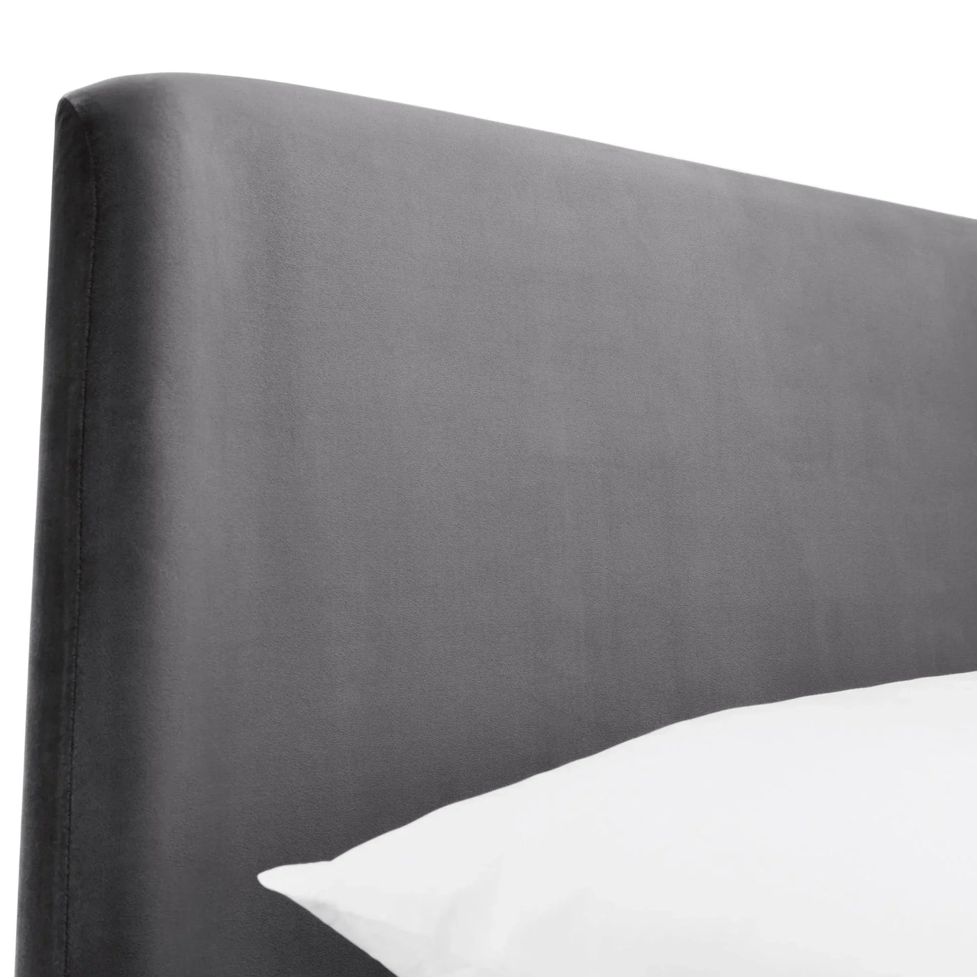 Close-up of grey velvet king bed headboard with pillow visible