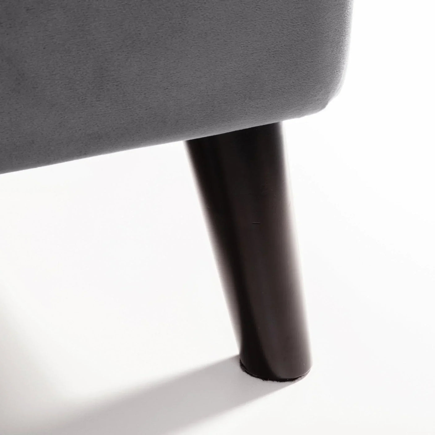 Grey velvet king bed close-up showing black wooden leg detail