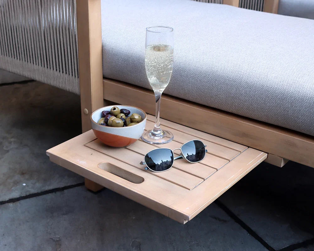 Outdoor sofa with wooden side table, bowl of olives, sunglasses, and glass of sparkling drink