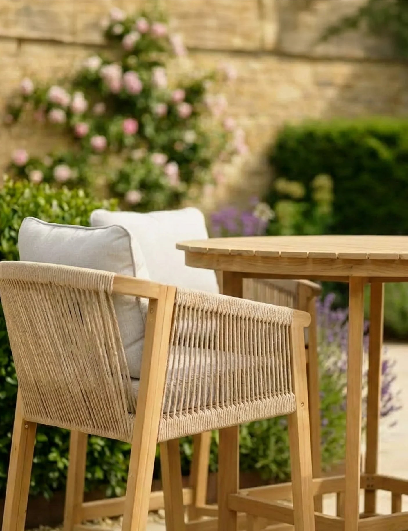 Rope outdoor dining chair with cushion beside wooden garden table, patio setting