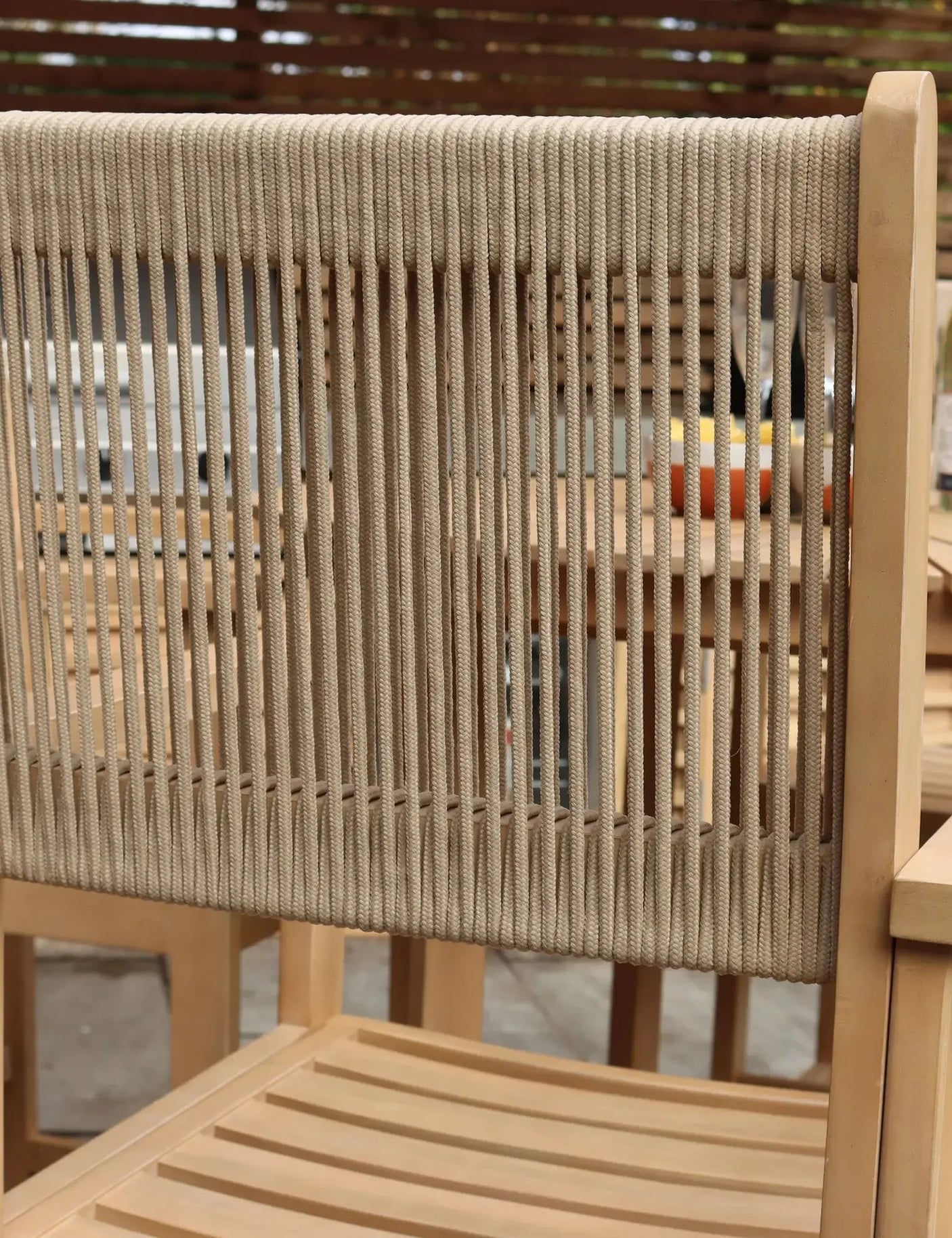 Outdoor dining chair with rope backrest and wooden frame, close-up on slatted seat