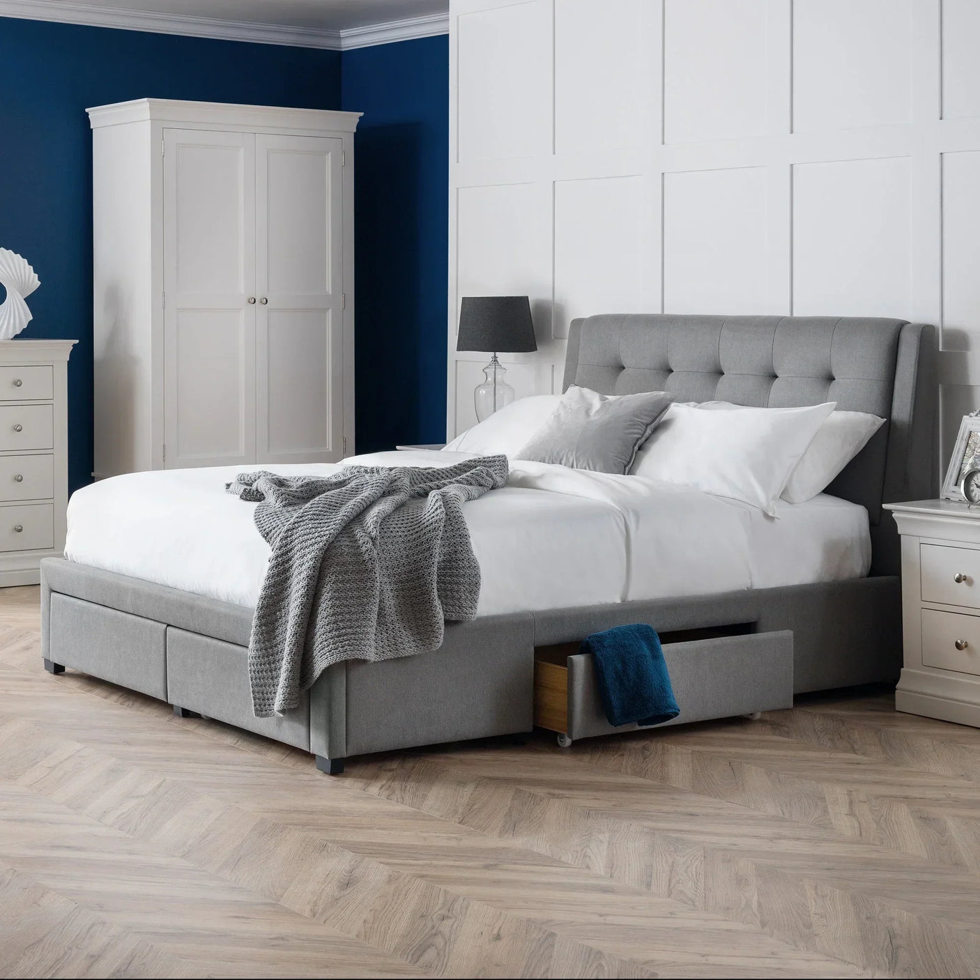 Grey double bed with four storage drawers, upholstered headboard, in modern bedroom setting
