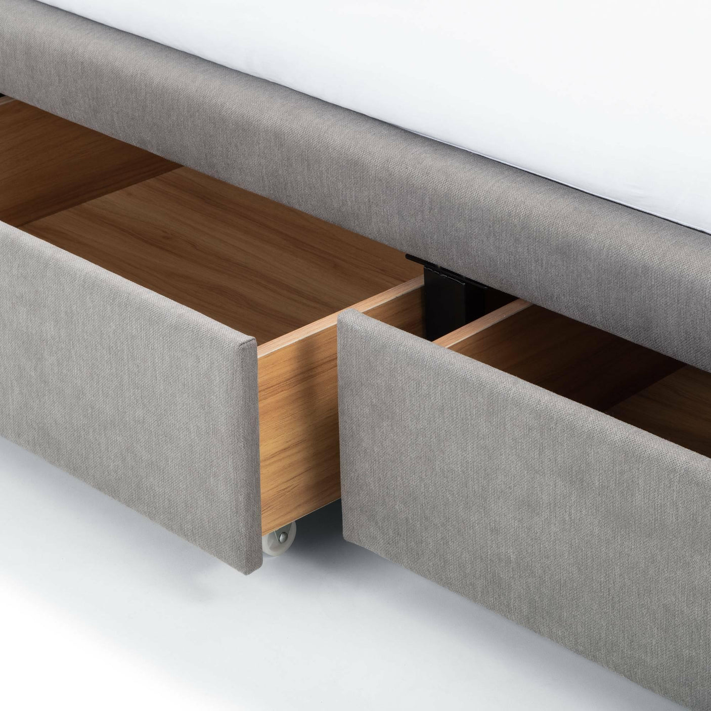 Grey double bed with fabric upholstery showing open storage drawers on wheels