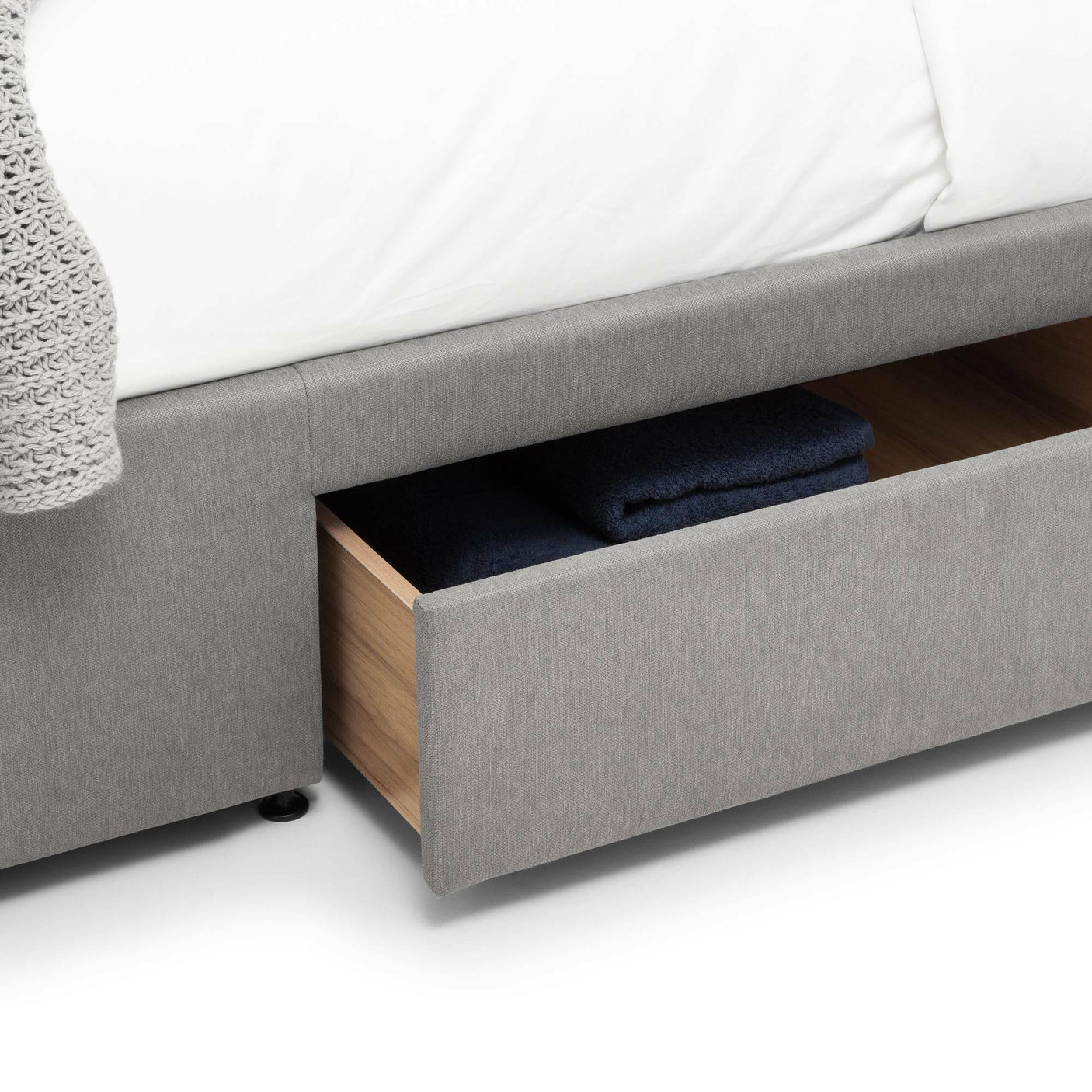 Grey double bed with open storage drawer showing folded towels inside