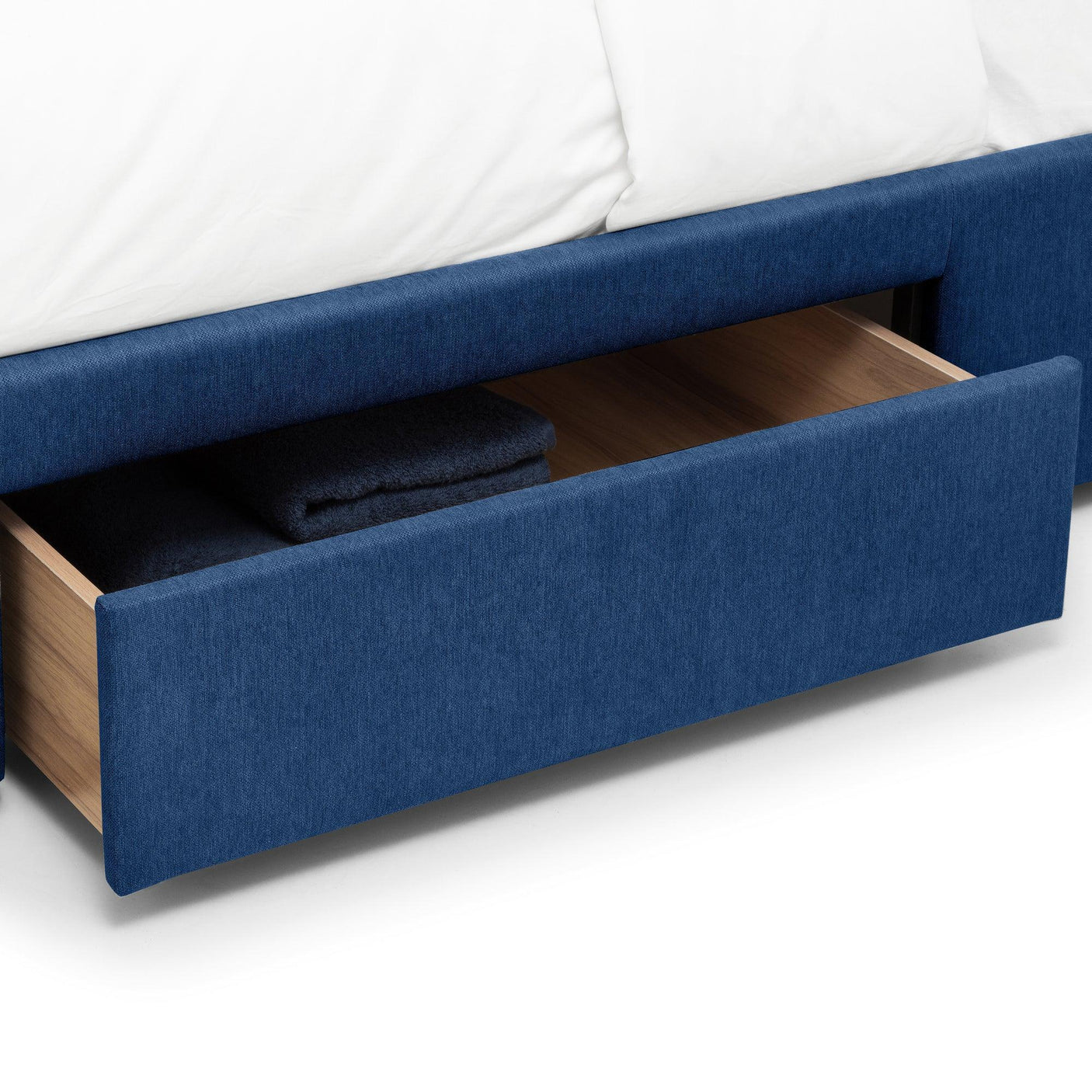 Blue double bed with storage drawer open showing folded blankets
