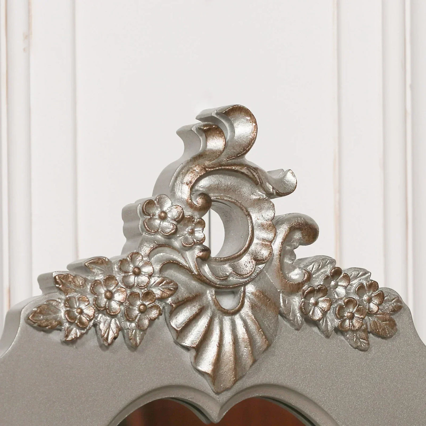 Silver ornate mirror frame with floral and scroll detailing close-up
