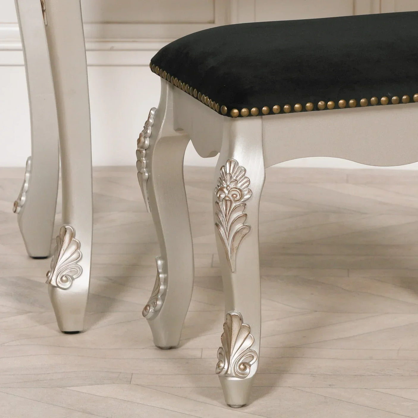 Silver carved dining chair legs with black upholstered seat and brass stud detail