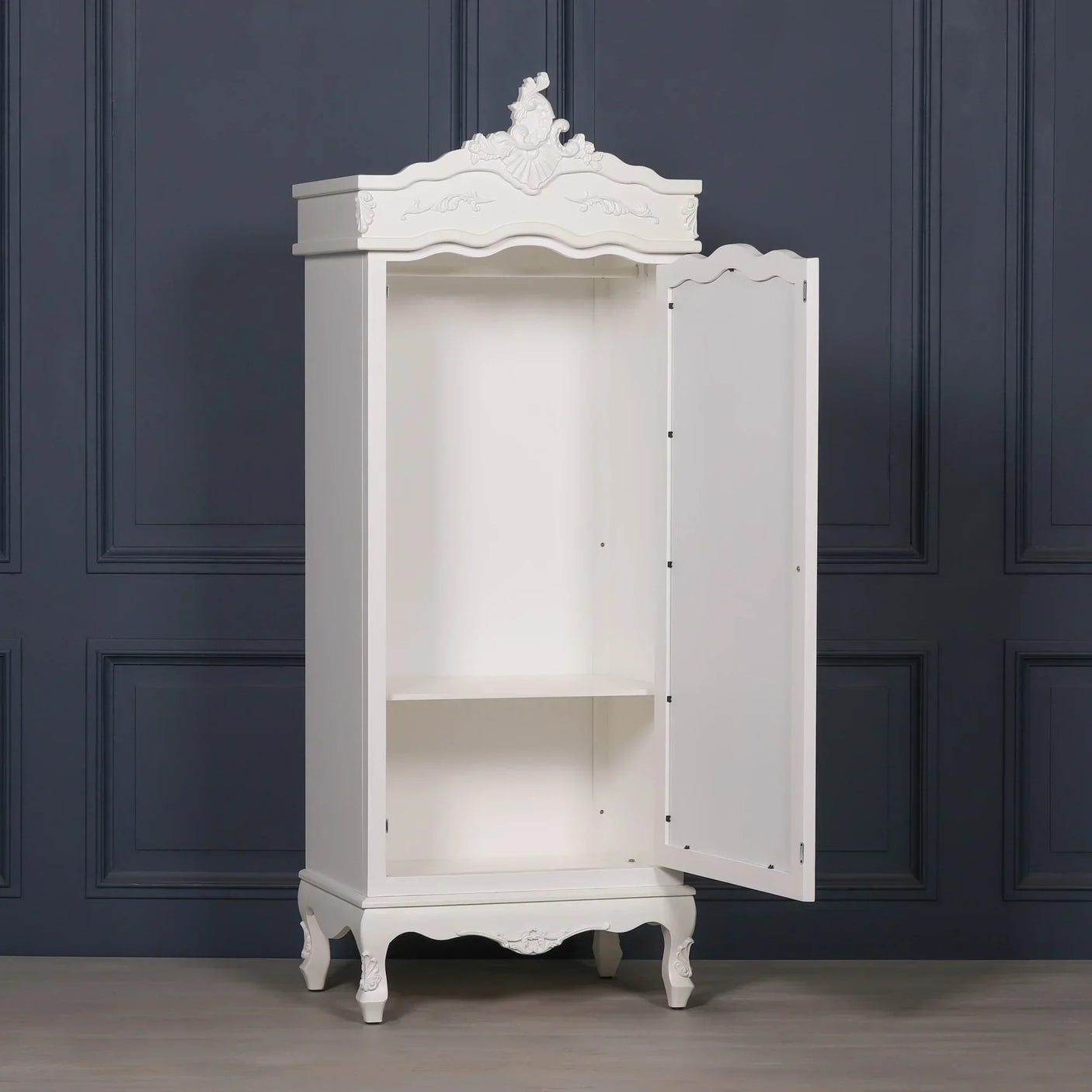 White wooden wardrobe with open door, ornate detailing, and single interior shelf