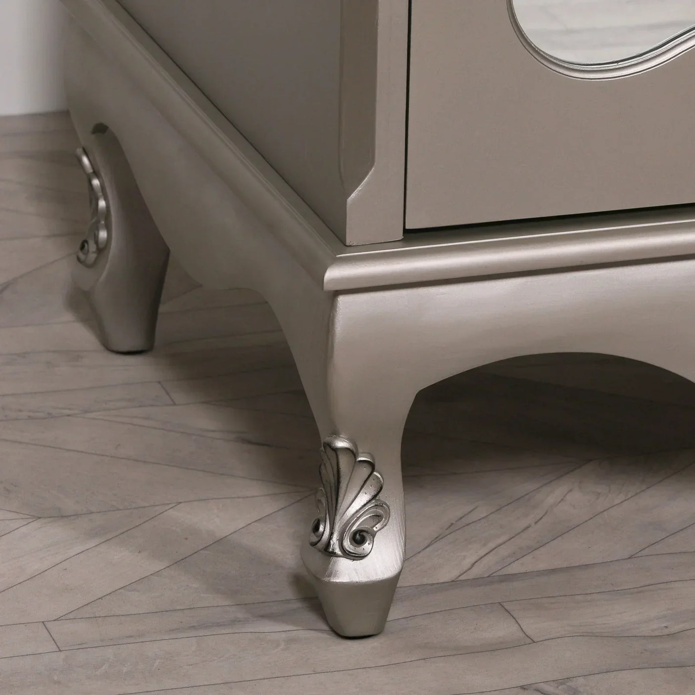 Silver chest of drawers corner with ornate carved legs on wood floor