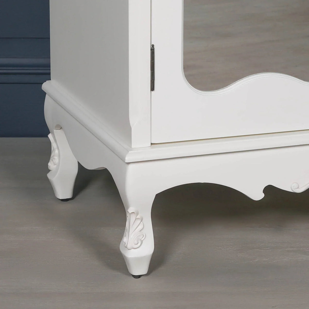 White wooden cabinet with curved carved legs and decorative detailing on base