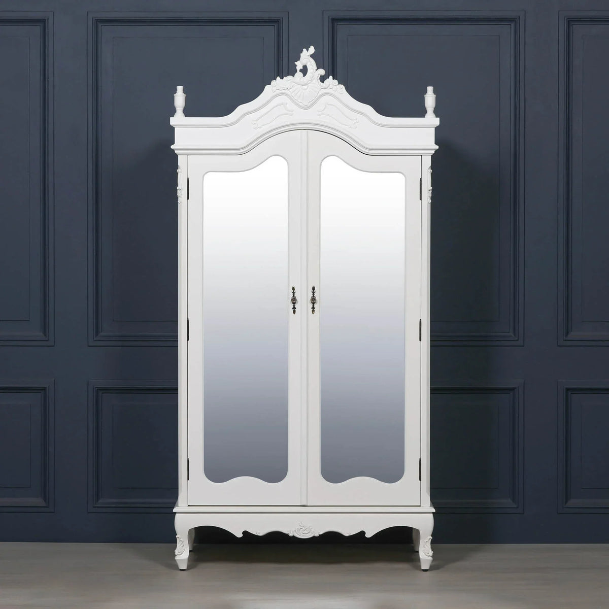 White mirrored wardrobe with ornate detailing and two doors against a dark panelled wall